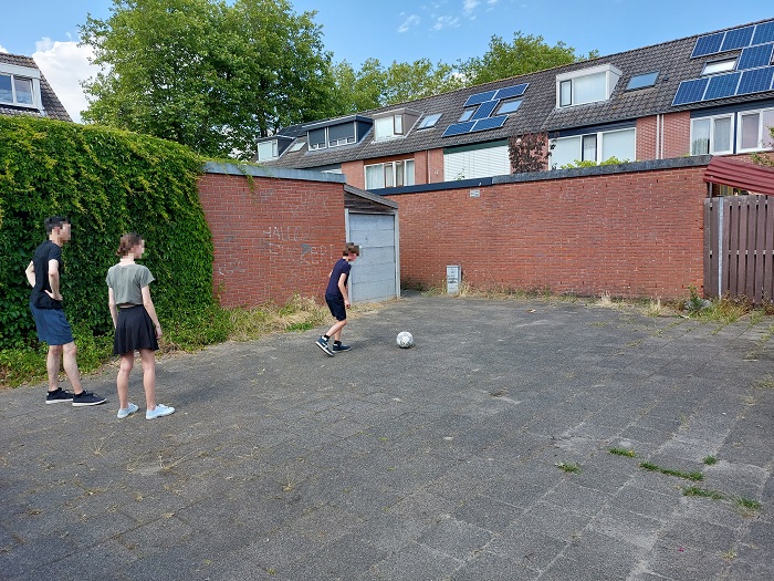 Drie jongens spelen met een bal in de buurt